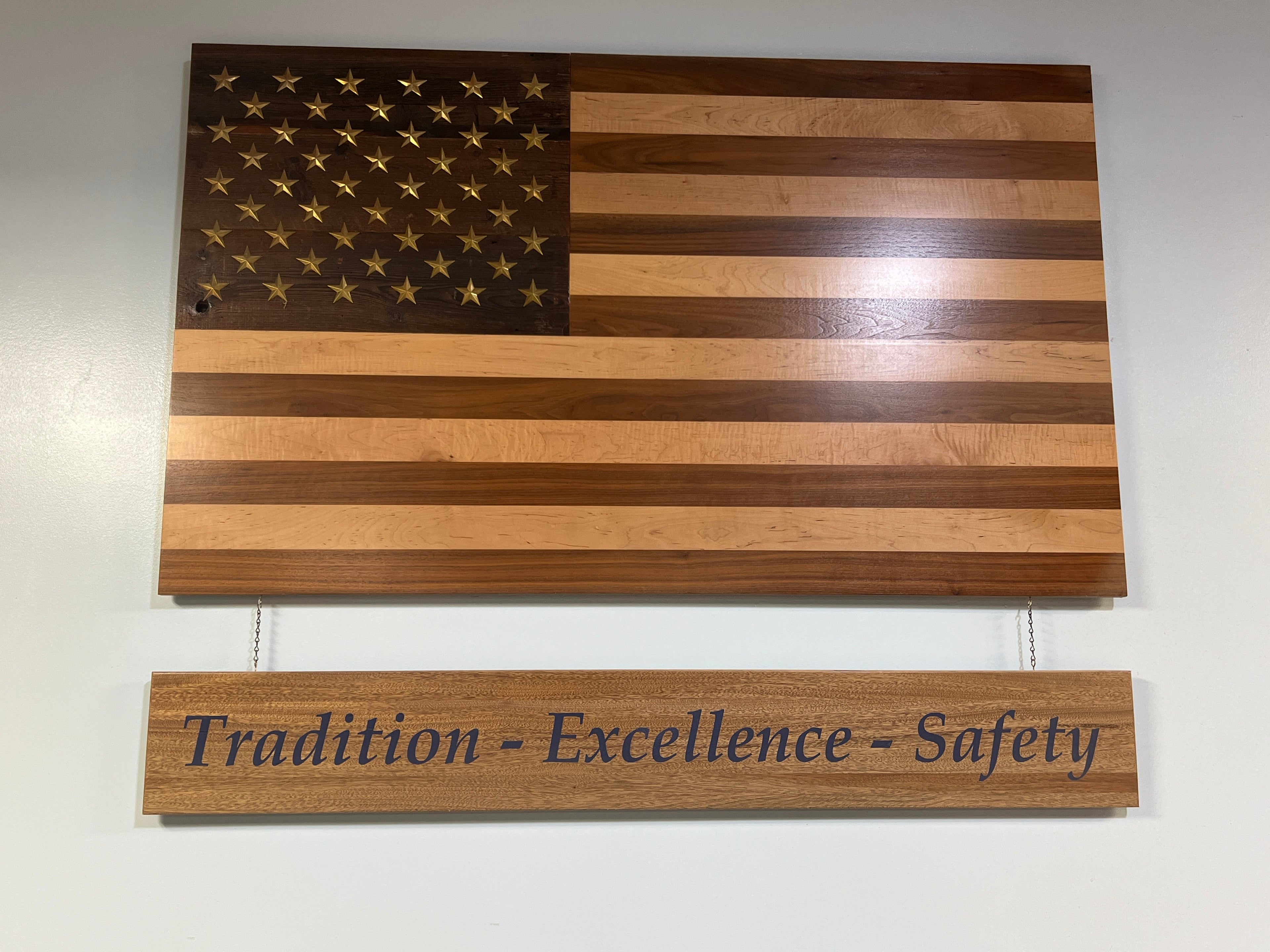 Handcrafted solid wood American flag with walnut and maple stripes, brass stars, and a reclaimed barn wood star background.