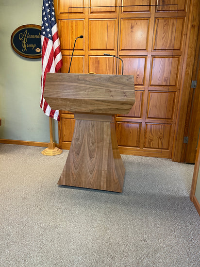 "StatesMan AutoGlide™ Height Adjustable Lift Podium, featuring a smooth, modern design with a sleek lift mechanism, allowing easy adjustment for different speaker heights and creating a versatile and professional presentation space. American made craftsmanship