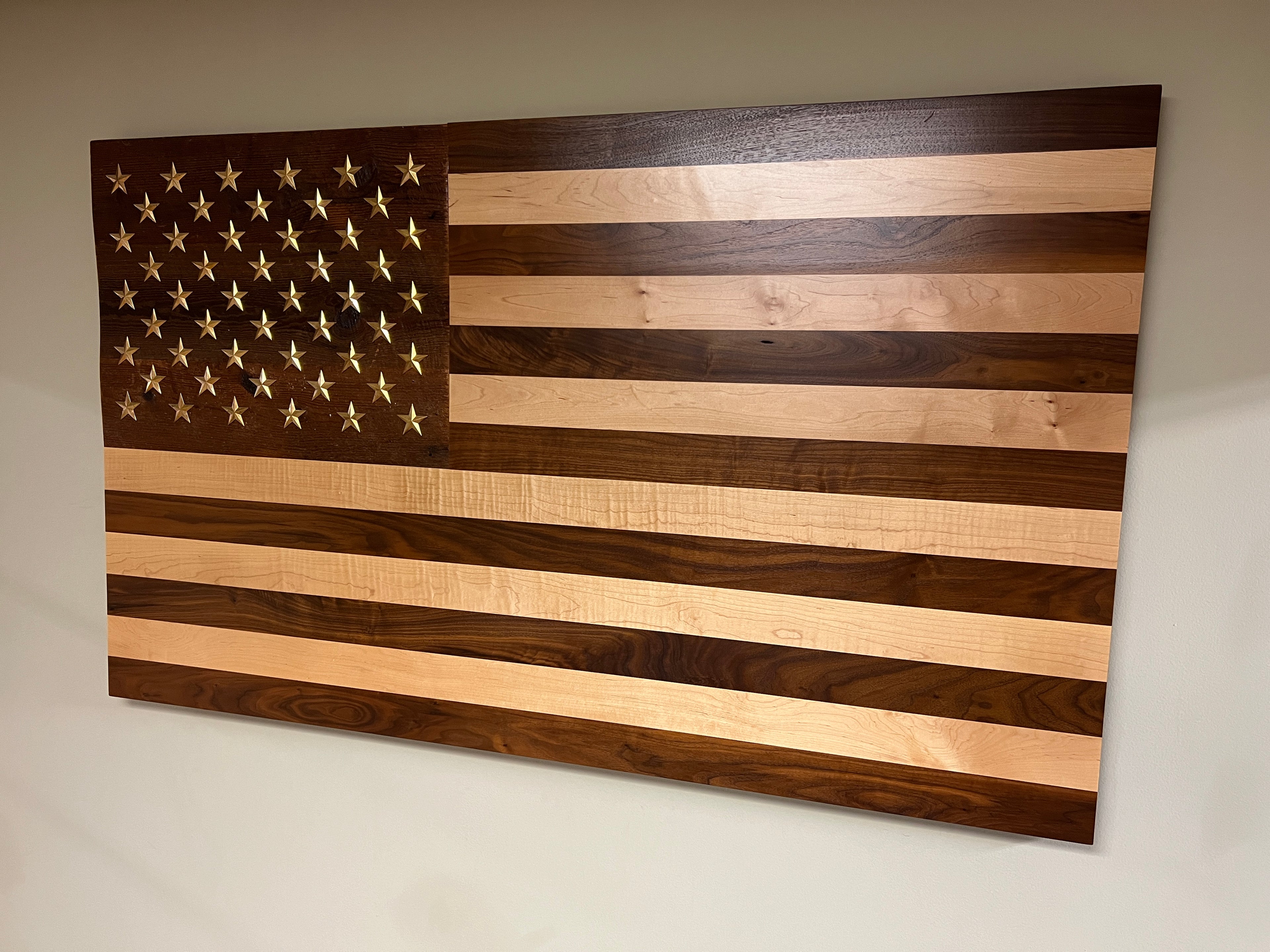 Handcrafted solid wood American flag with walnut and maple stripes, brass stars, and a reclaimed barn wood star background.