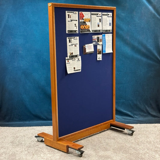 Blue ballistic notice board with wooden frame and wheels against a blue background