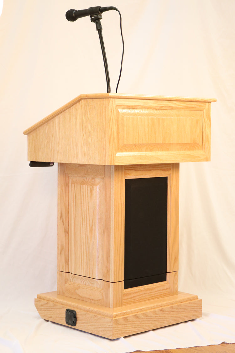 The Counselor Evolution Lift™ lectern, handcrafted from oak wood, features adjustable height, built-in sound system, and mobility casters.