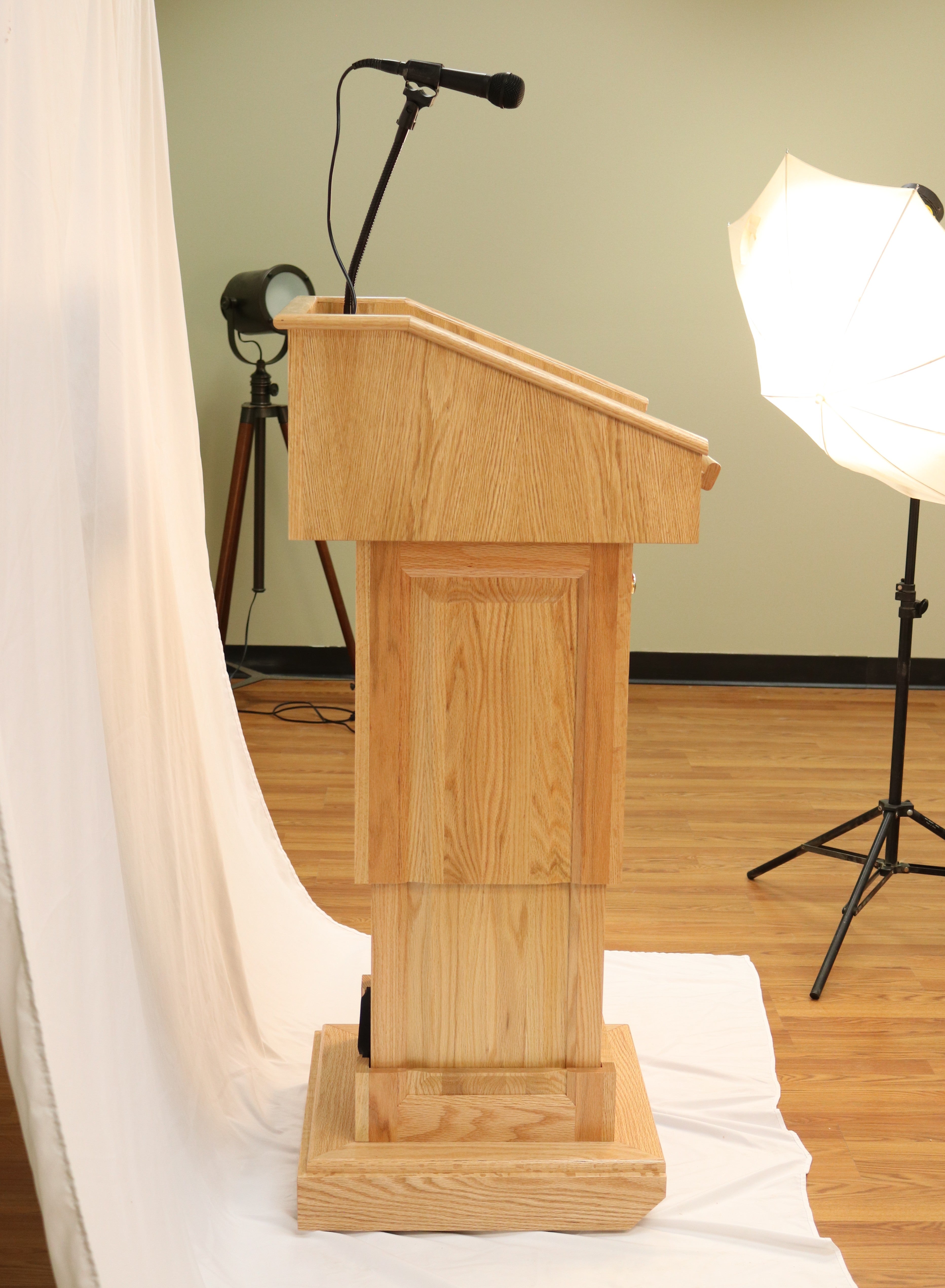 The Counselor Evolution Lift™ lectern, handcrafted from oak wood, features adjustable height, built-in sound system, and mobility casters.